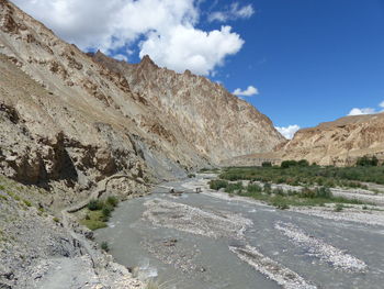 Scenic view of road by mountains against sky