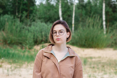 Candid close up portrait of a young woman with short hair in eyeglasses on nature