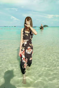 Woman standing at beach against sky