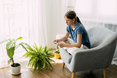 A young girl is sitting in a chair and exchanging messages online on her phone. home recreation