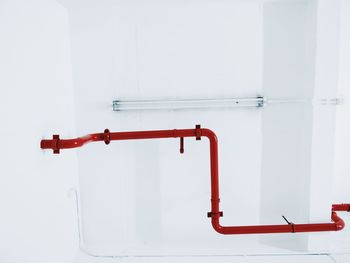 Directly below shot of red pipe against white ceiling