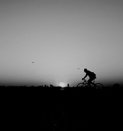 Silhouette man riding bicycle against clear sky