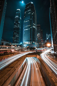 Light trails on road amidst illuminated buildings in city at night