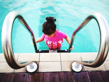 High angle view of girl standing by railing in swimming pool