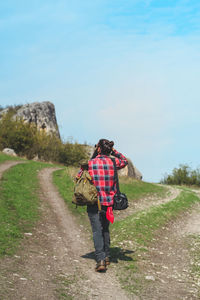 Rear view of woman walking on road against sky