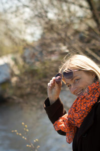 Portrait of woman wearing sunglasses looking at lake