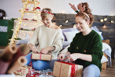 Sisters opening christmas presents while sitting at home