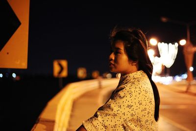 Portrait of young woman looking away at night