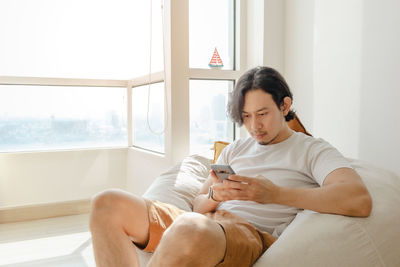 Man using mobile phone sitting on bean bag at home