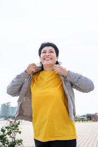 Portrait of a smiling young woman standing against clear sky