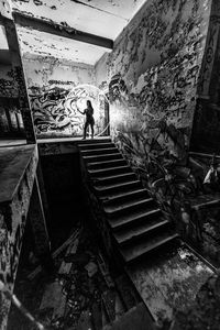 High angle view of woman standing on staircase in abandoned building