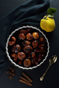 Baked quinces in bakeware,raw quince,cinnamon sticks and star anise, gold spoon 