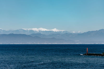 Scenic view of sea and mountains against clear blue sky