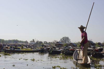 Man on boat in river against clear sky