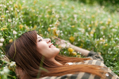 High angle view of carefree young woman lying down on grassy field