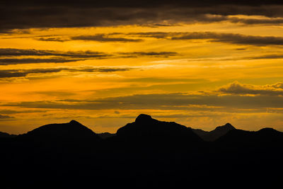 Scenic view of silhouette mountains against orange sky