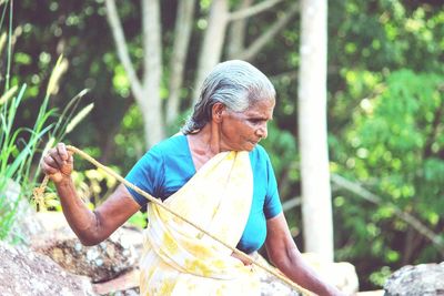 Senior woman with rope standing in yard