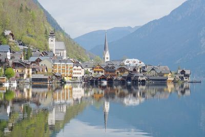 Houses by lake and mountains against sky