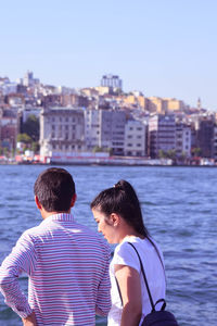 Rear view of friends against cityscape against sky