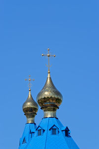 Gold colored cupola with religious cross against clear blue sky