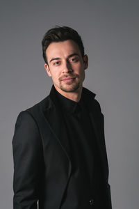 Portrait of young man standing against gray background