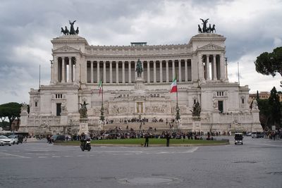 Statue in front of historical building against cloudy sky