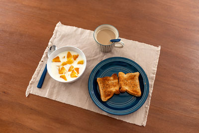 Healthy breakfast with orange, coffee and toasts, on wood.