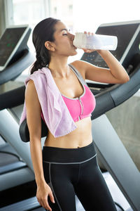 Full length of a young woman drinking water