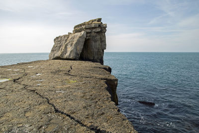 Rock formation on sea shore against sky