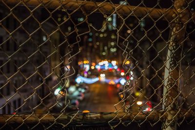 Illuminated lights seen through chainlink fence at night