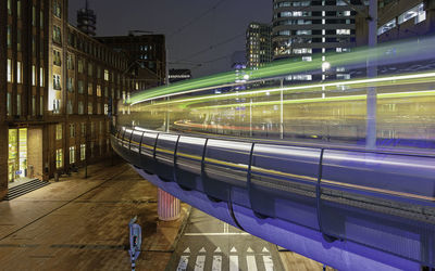 Train on illuminated street in city at night