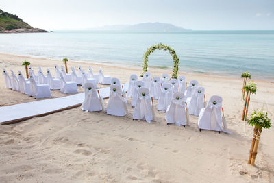 Deck chairs on beach against sky