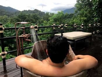 Rear view of woman sitting on railing against mountain