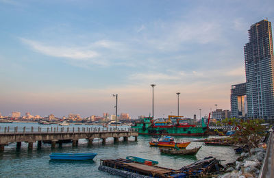 Boats moored in city against sky during sunset