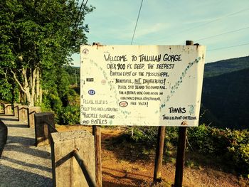 Information sign on tree against sky