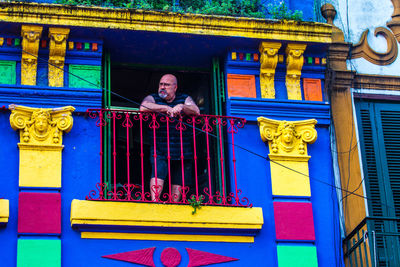 Portrait of man standing by railing against building