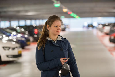 Full length of woman using remote key to lock car in parking lot