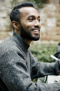 Side view of smiling young man with hair stubble at garden party