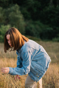 Side view of young woman standing on field