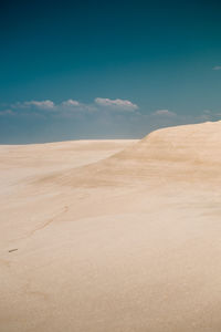 Sand dunes at the beach with white sand and blue sky.