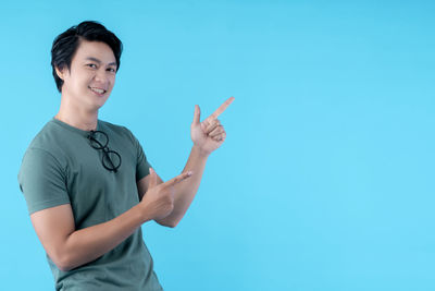 Portrait of young man standing against blue background