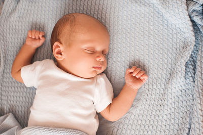 Directly above shot of baby boy sleeping on bed at home