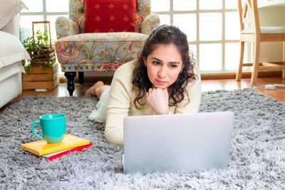 Portrait of young woman using mobile phone while sitting on table