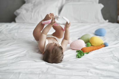 Girl playing while lying on bed at home