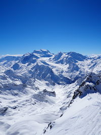 Scenic view of snow covered mountains against clear blue sky