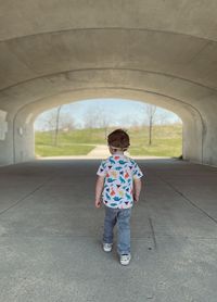Rear view of toddler boy walking through tunnel