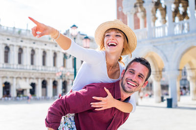 Smiling couple embracing against historic building
