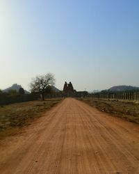 Empty road amidst field against clear sky