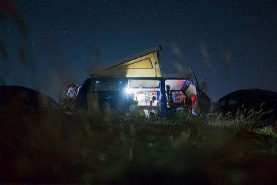 People photographing illuminated car on land against sky at night