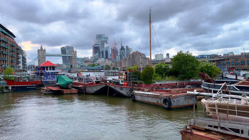 Buildings by river against cloudy sky